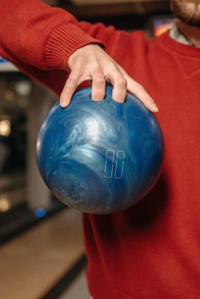 Een persoon die een bowlingbal vastheeft met twee vingers in de bal